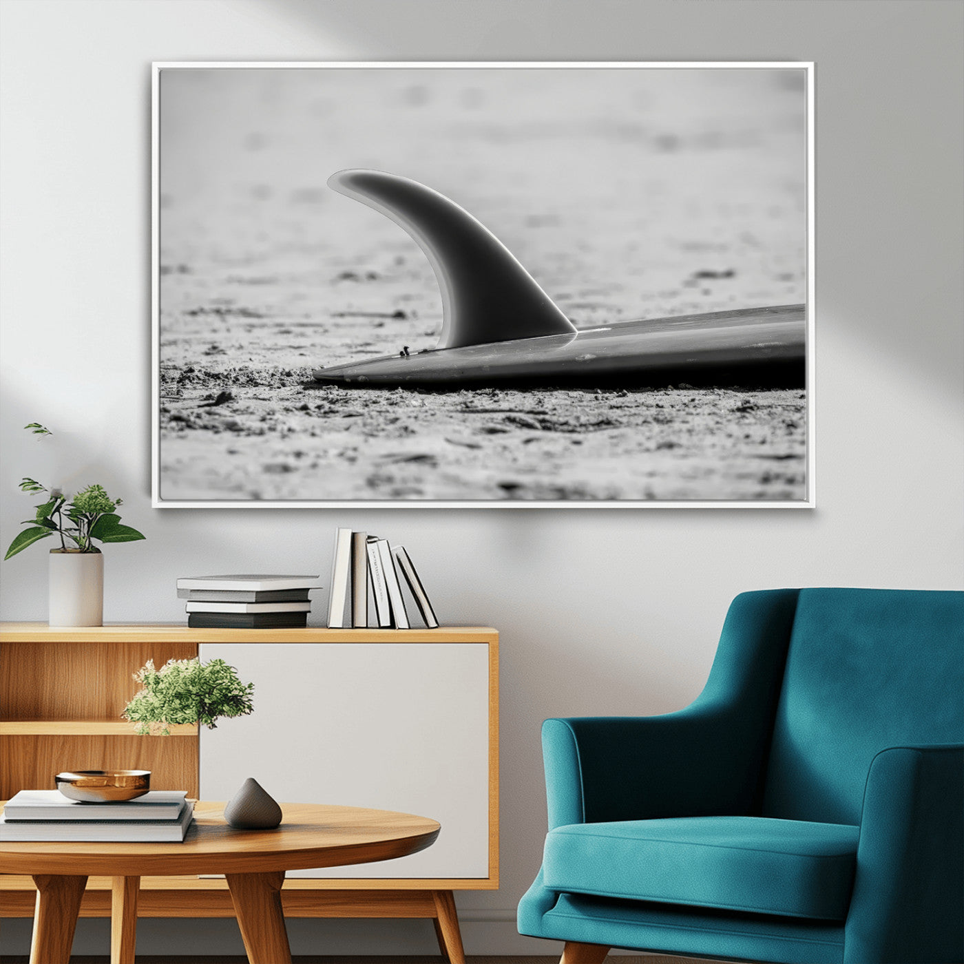 A black and white close-up of a surfboard fin resting on the sandy shore, highlighting minimalist beach aesthetics and classic surf culture.