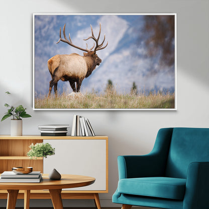 Elk with antlers standing on grass with mountain background, ideal for rustic, cabin, or lodge-inspired wall decor.