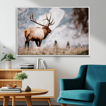 Majestic elk with large antlers standing in grass with snowy mountains in background, perfect for rustic cabin or lodge style decor.