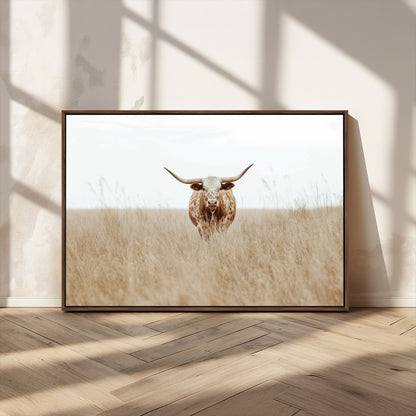 Texas Longhorn bull standing alone in dry grass with neutral tones, ideal for rustic western or cowboy-themed wall decor.