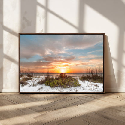 A tranquil beach scene featuring golden sunset hues over the water, with grasses in the foreground and a peaceful, serene atmosphere.