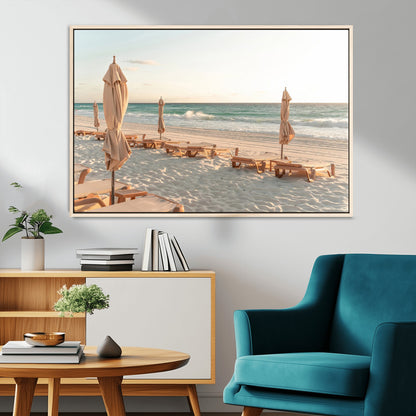 Minimalist photo of empty beach loungers and umbrellas on soft sand, ideal for calm seaside or pastel coastal-style home decor.