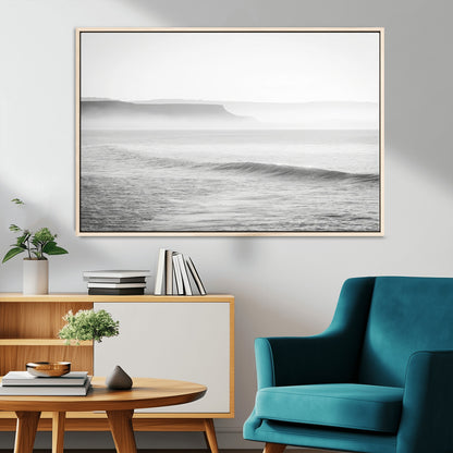 A black and white minimalist seascape featuring soft rolling waves and misty distant cliffs, creating a serene and timeless coastal atmosphere.