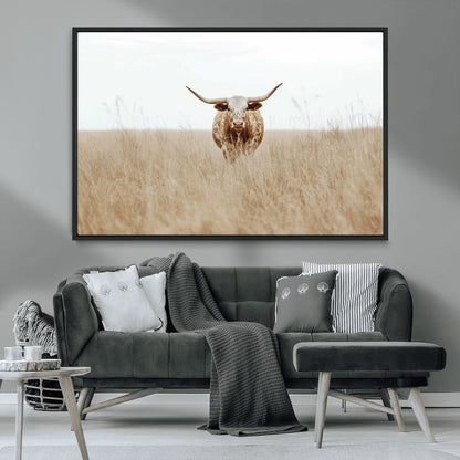 Texas Longhorn bull standing alone in dry grass with neutral tones, ideal for rustic western or cowboy-themed wall decor.
