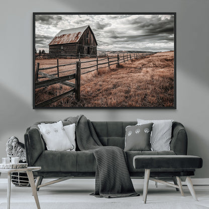 Framed canvas of a rustic barn under a moody sky with weathered fence and dark fields, ideal for farmhouse or rural-style wall decor.