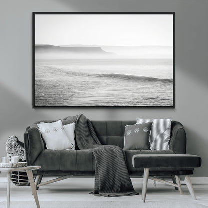A black and white minimalist seascape featuring soft rolling waves and misty distant cliffs, creating a serene and timeless coastal atmosphere.