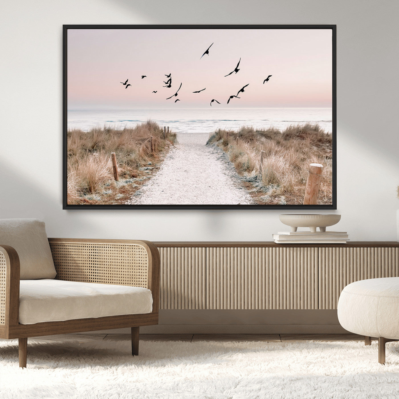 A peaceful coastal pathway leading to the ocean, with birds flying across a soft pastel sky, creating a calm and scenic beach atmosphere.