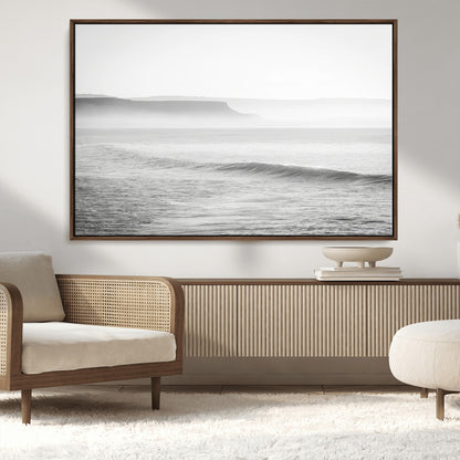 A black and white minimalist seascape featuring soft rolling waves and misty distant cliffs, creating a serene and timeless coastal atmosphere.