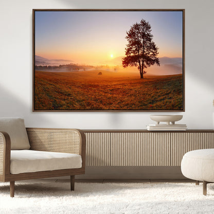 A tranquil landscape at sunrise with a mist-covered field and a lone tree, creating a peaceful and natural atmosphere.