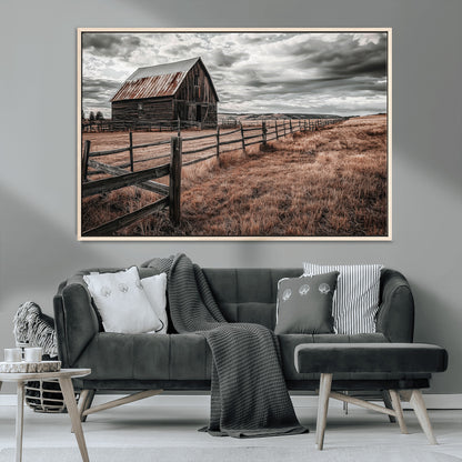 Framed canvas of a rustic barn under a moody sky with weathered fence and dark fields, ideal for farmhouse or rural-style wall decor.