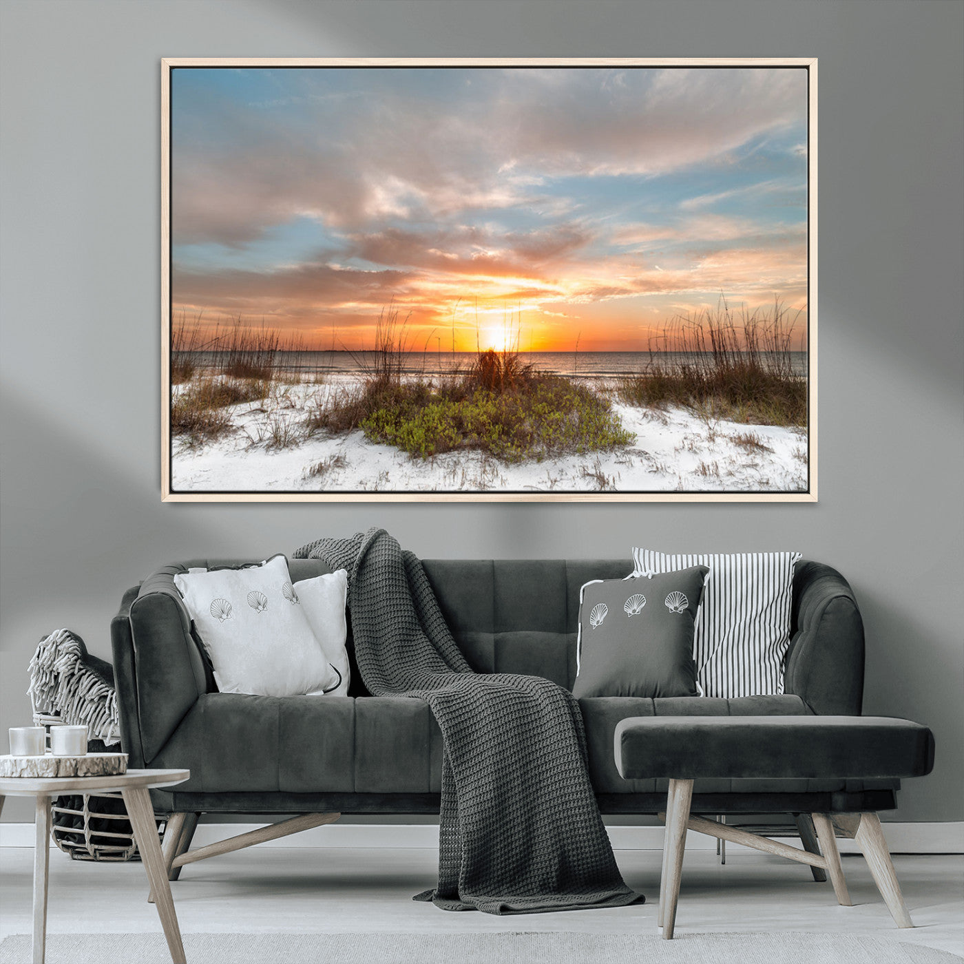 A tranquil beach scene featuring golden sunset hues over the water, with grasses in the foreground and a peaceful, serene atmosphere.
