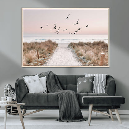 A peaceful coastal pathway leading to the ocean, with birds flying across a soft pastel sky, creating a calm and scenic beach atmosphere.