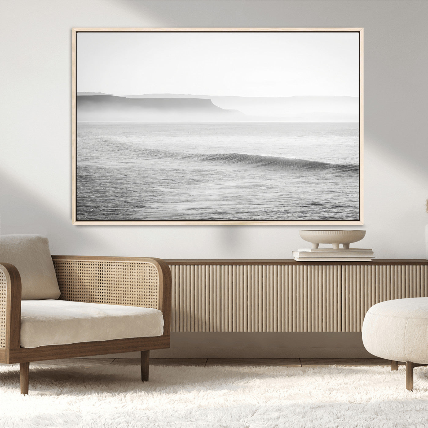 A black and white minimalist seascape featuring soft rolling waves and misty distant cliffs, creating a serene and timeless coastal atmosphere.