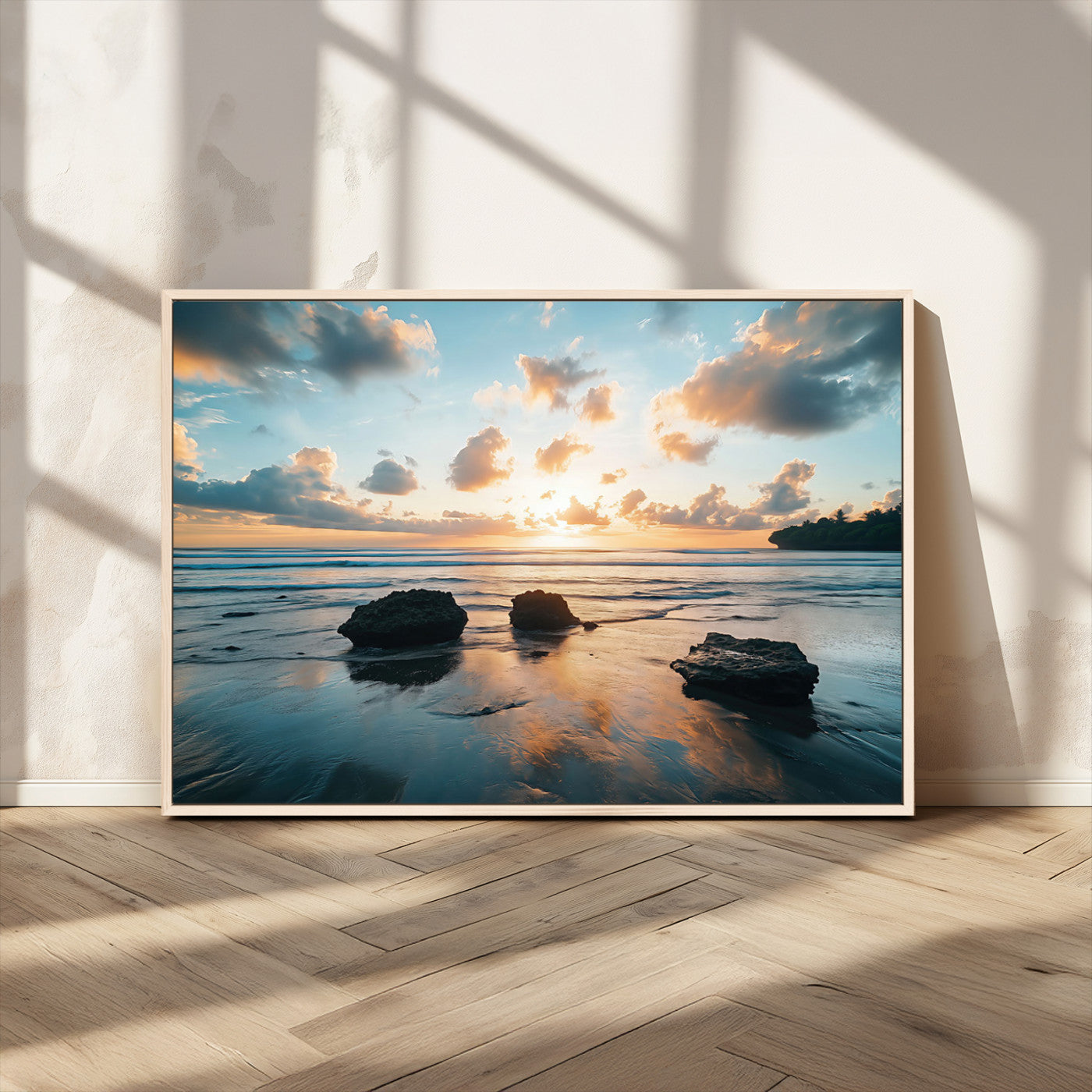 A serene beach at sunset with vibrant clouds, calm water, and rocks in the foreground reflecting the warm colors of the setting sun.