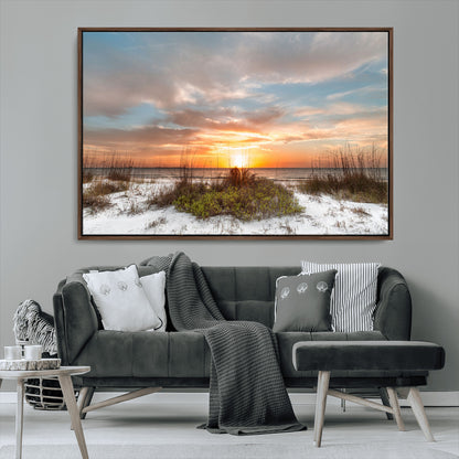 A tranquil beach scene featuring golden sunset hues over the water, with grasses in the foreground and a peaceful, serene atmosphere.