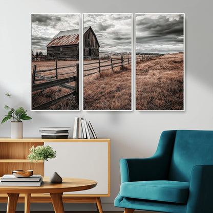Framed canvas of a rustic barn under a moody sky with weathered fence and dark fields, ideal for farmhouse or rural-style wall decor.