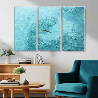Aerial view of a shark swimming through a swirl of fish in clear turquoise waters, perfect for calm coastal or beach house decor.