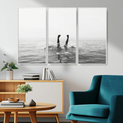 A black and white minimalist water scene capturing a playful splash as a swimmer dives upside down, creating a carefree and artistic aquatic aesthetic.