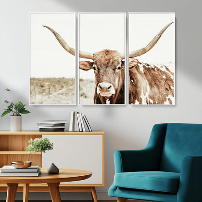 A Texas longhorn bull with wide horns, standing in a dry field under soft light, ideal for rustic farmhouse or western-themed interiors.