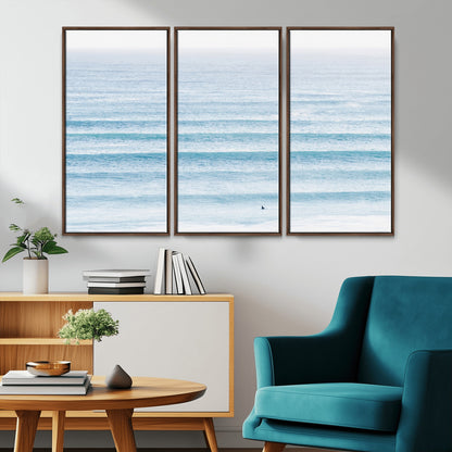 Minimalist ocean view with soft blue waves and a lone surfer, creating a serene and airy coastal aesthetic, perfect for tranquil home decor.