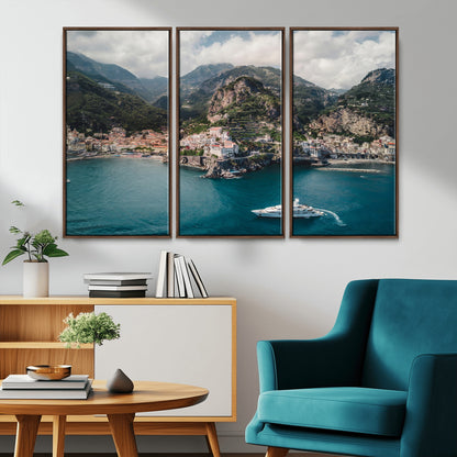 Aerial view of Amalfi Coast, Italy, with colorful hillside houses, lush green mountains, and a luxury yacht sailing in turquoise waters.