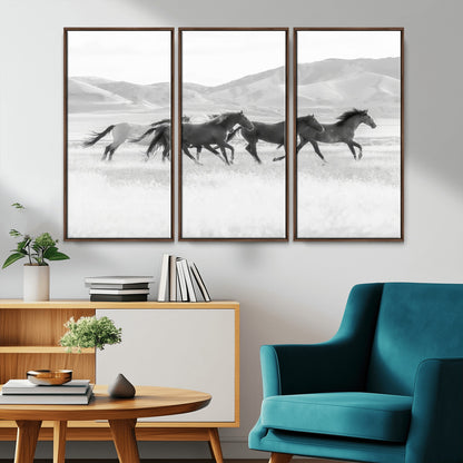 A black and white image of wild horses running freely across an open grassland, capturing the power and beauty of untamed nature in a rustic western setting.