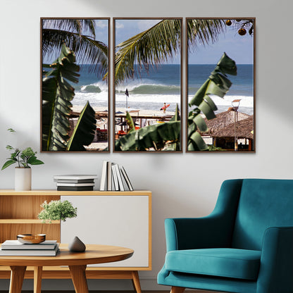 Canvas wall art of a tropical surf scene framed by palm trees, with a surfer on the shore and waves rolling in, ideal for beach-themed decor.