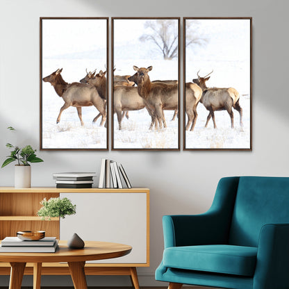 A group of elk standing on snowy terrain with a tree in the background, perfect for rustic or lodge-style winter wall decor.