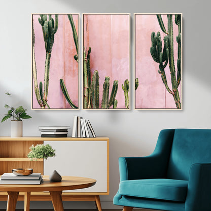 Framed canvas of tall green cacti against a soft pink wall, ideal for modern desert or colorful southwest-inspired home decor.