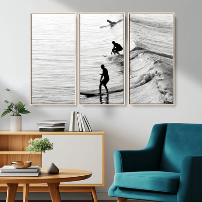 Black and white photo of surfers riding waves in a moody, high-contrast scene, ideal for modern coastal or surf-inspired home decor.