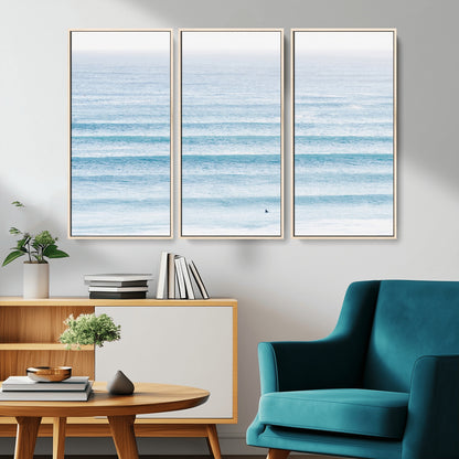 Minimalist ocean view with soft blue waves and a lone surfer, creating a serene and airy coastal aesthetic, perfect for tranquil home decor.