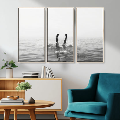A black and white minimalist water scene capturing a playful splash as a swimmer dives upside down, creating a carefree and artistic aquatic aesthetic.