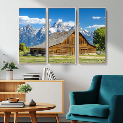 A rustic wooden barn sits in front of towering mountain peaks under a clear blue sky, perfect for farmhouse or cabin style interiors.