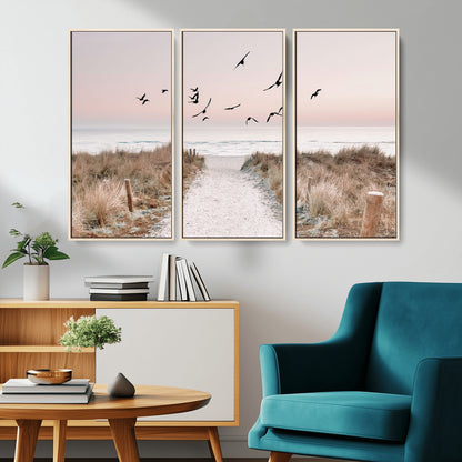A peaceful coastal pathway leading to the ocean, with birds flying across a soft pastel sky, creating a calm and scenic beach atmosphere.