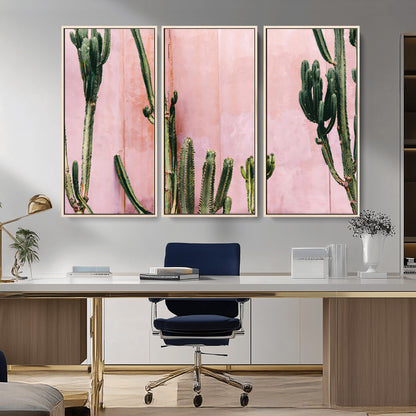 Framed canvas of tall green cacti against a soft pink wall, ideal for modern desert or colorful southwest-inspired home decor.