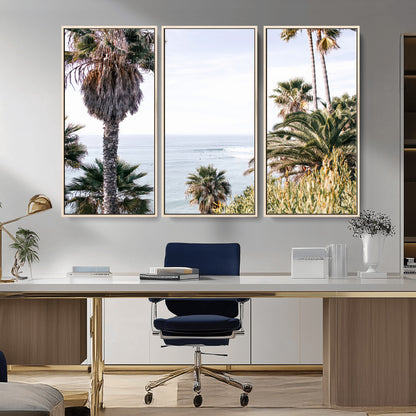 Scenic coastal view with tall palm trees overlooking a calm ocean, soft blue waves, and surfers in the distance, creating a peaceful tropical vibe.