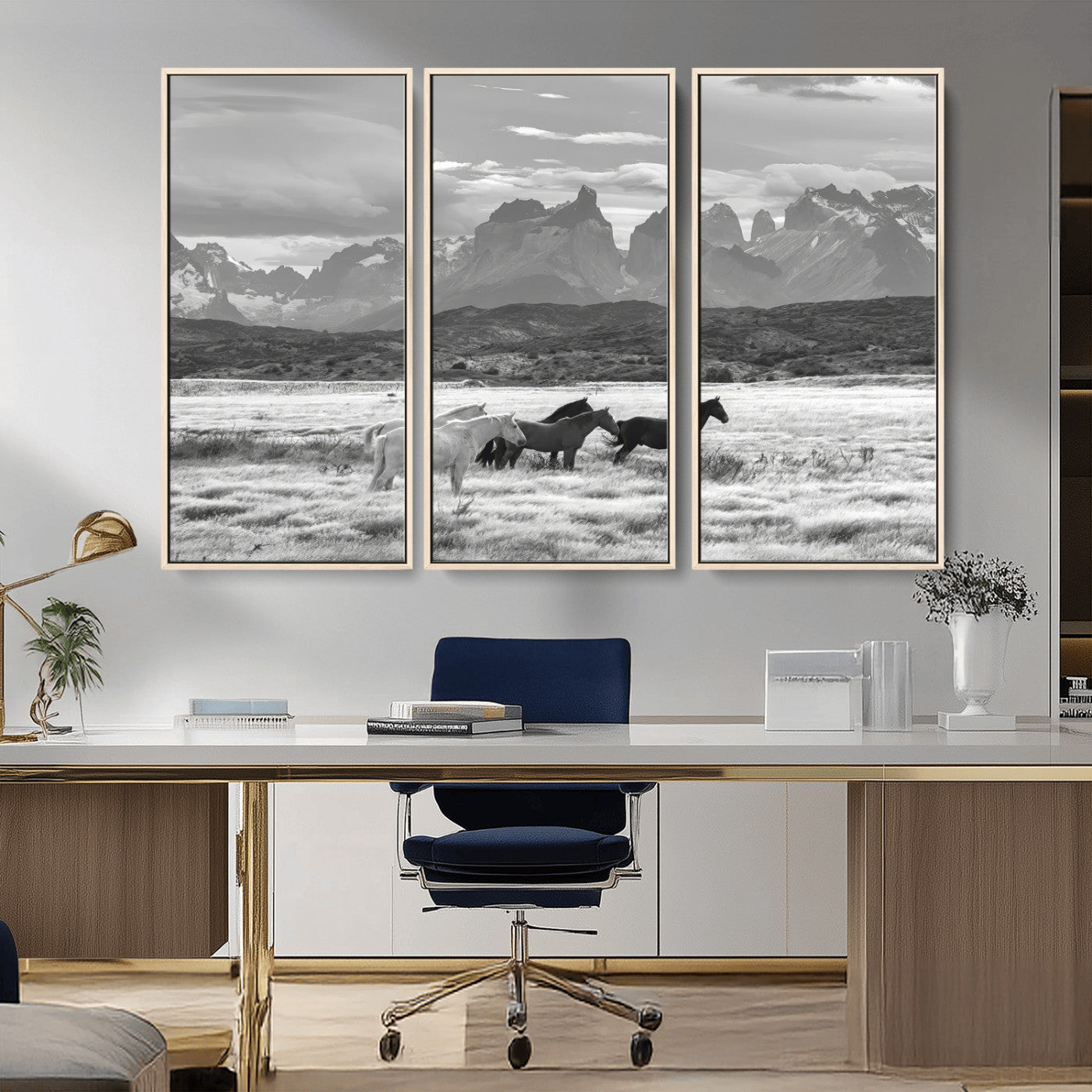 A black and white landscape of wild horses grazing in a vast grassland with towering mountains in the background, creating a moody and rustic western aesthetic.
