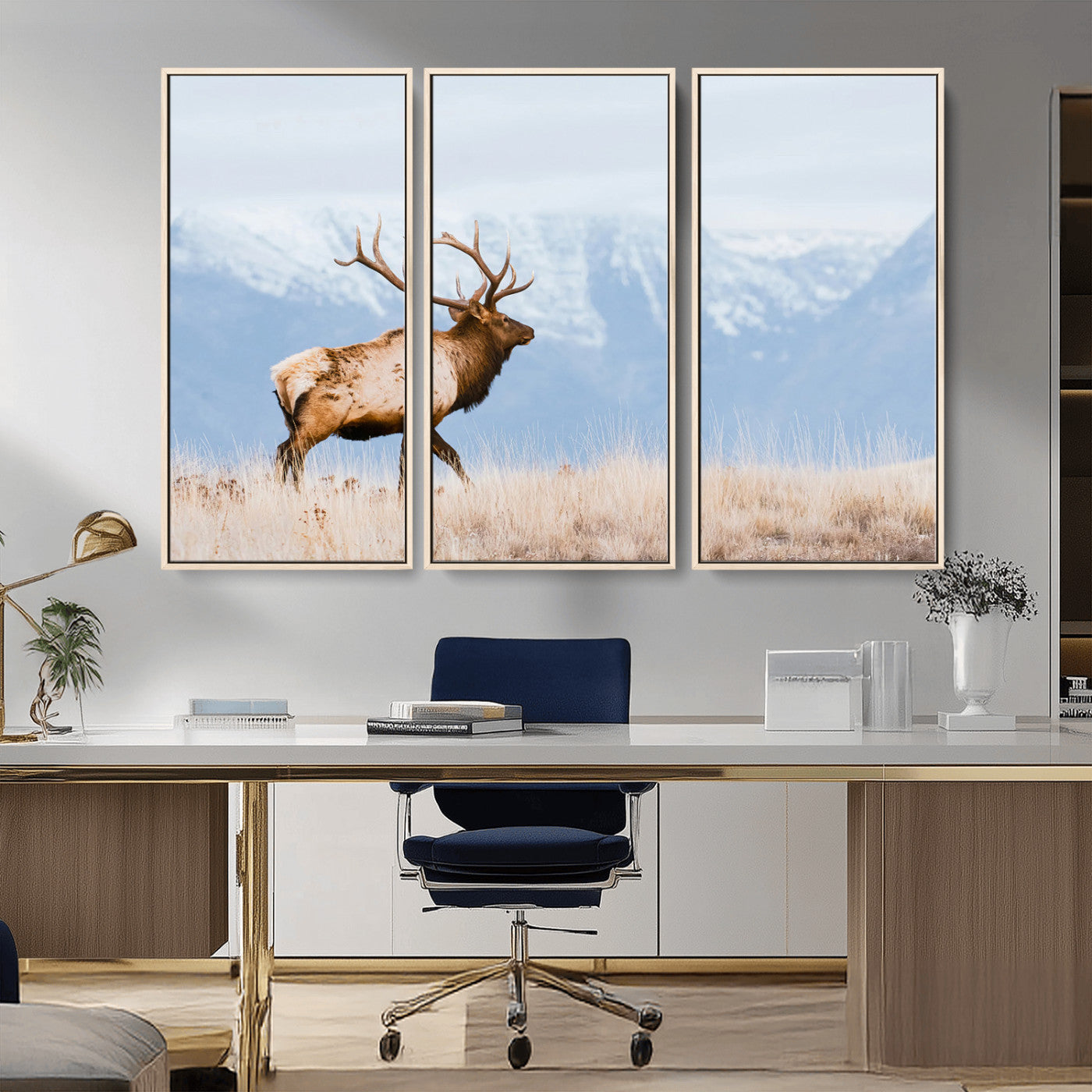 An elk walking on snowy grassland with majestic mountains in the background, ideal for rustic lodge or cabin wall decor.