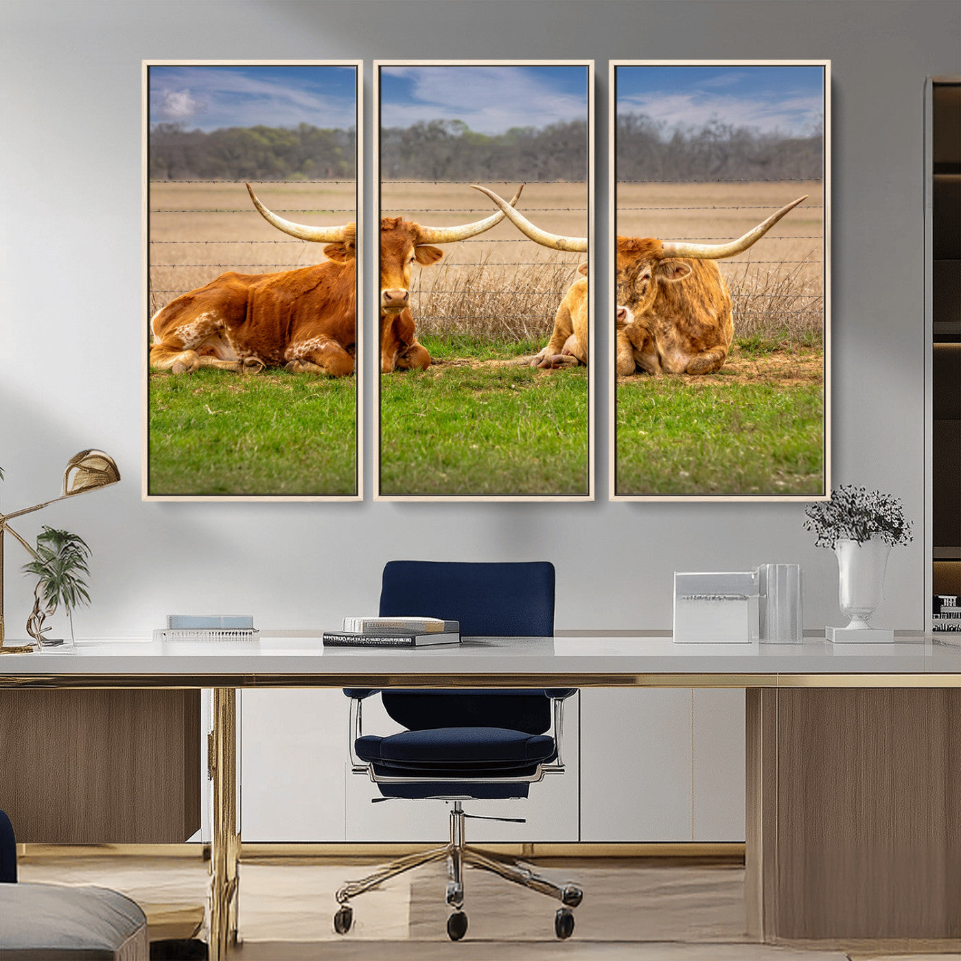 Two longhorn cows lying on green grass in front of a golden field and trees under a blue sky, perfect for rustic country wall decor.