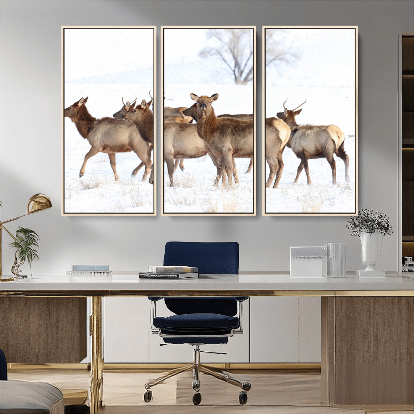 A group of elk standing on snowy terrain with a tree in the background, perfect for rustic or lodge-style winter wall decor.