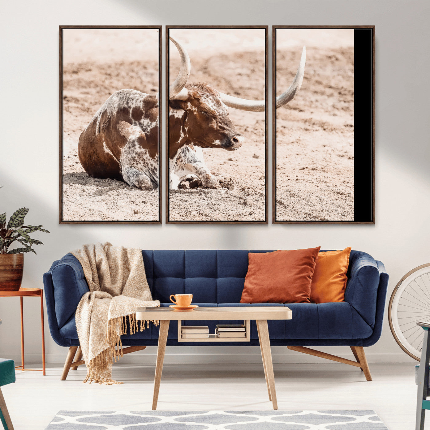 Texas Longhorn bull resting on dusty ground with warm tones, ideal for rustic western or farmhouse-themed wall decor.