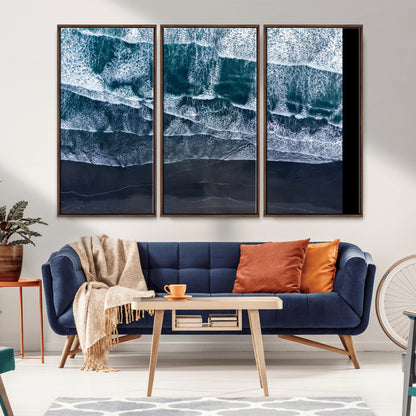 Canvas of aerial ocean waves crashing onto a black sand beach in moody tones, ideal for modern coastal or minimalist home decor.