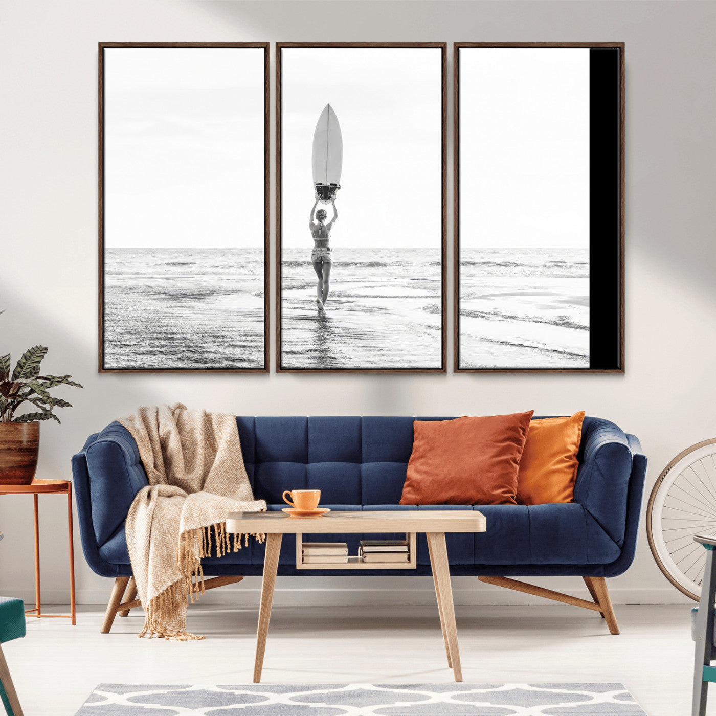 Black and white image of a female surfer holding a surfboard above her head while walking toward the ocean, creating a minimalist and bold coastal aesthetic.