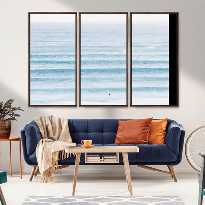 Minimalist ocean view with soft blue waves and a lone surfer, creating a serene and airy coastal aesthetic, perfect for tranquil home decor.