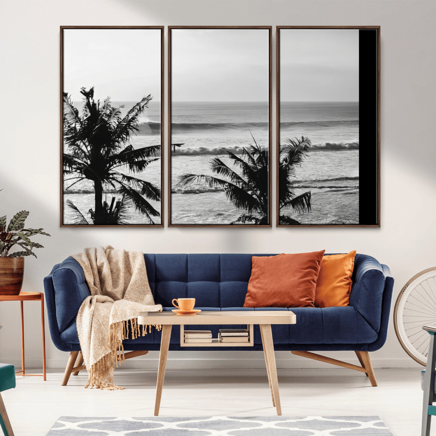 Black and white view of ocean waves crashing on a tropical coastline, framed by silhouetted palm trees under a vast, open sky.