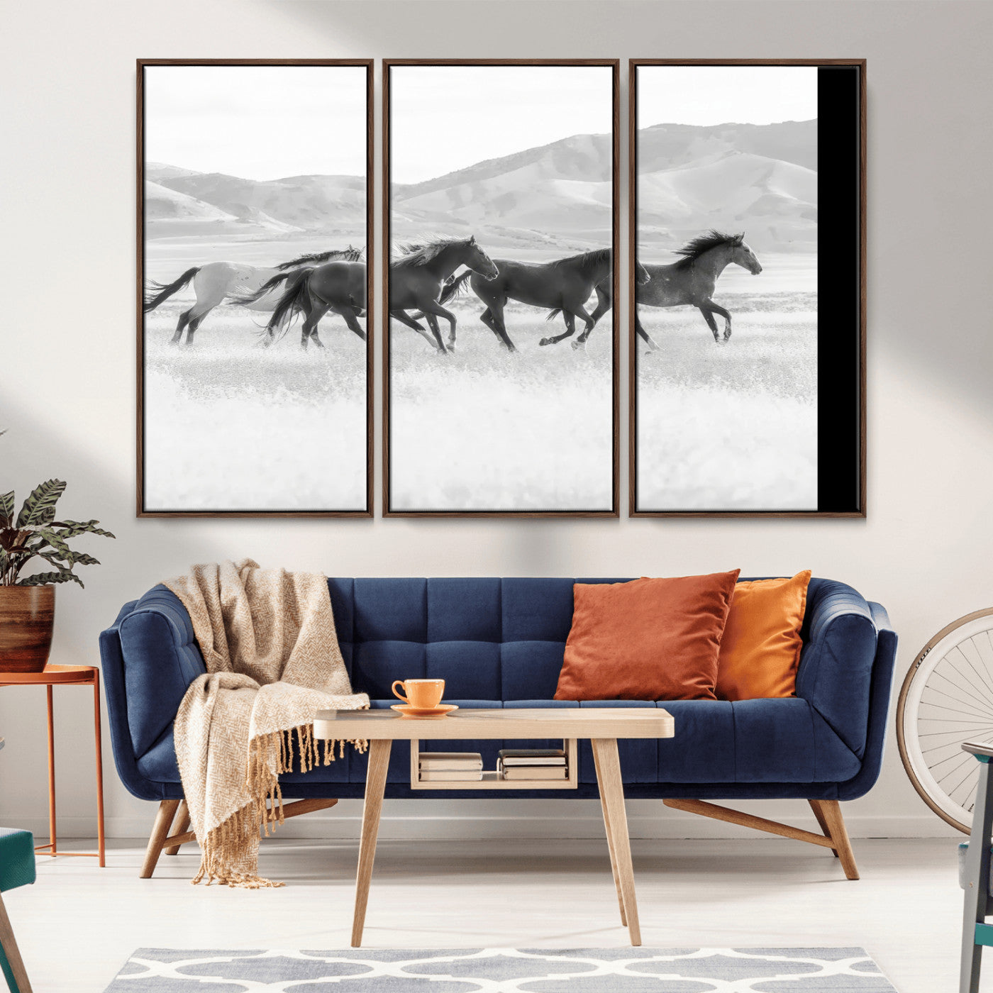 A black and white image of wild horses running freely across an open grassland, capturing the power and beauty of untamed nature in a rustic western setting.