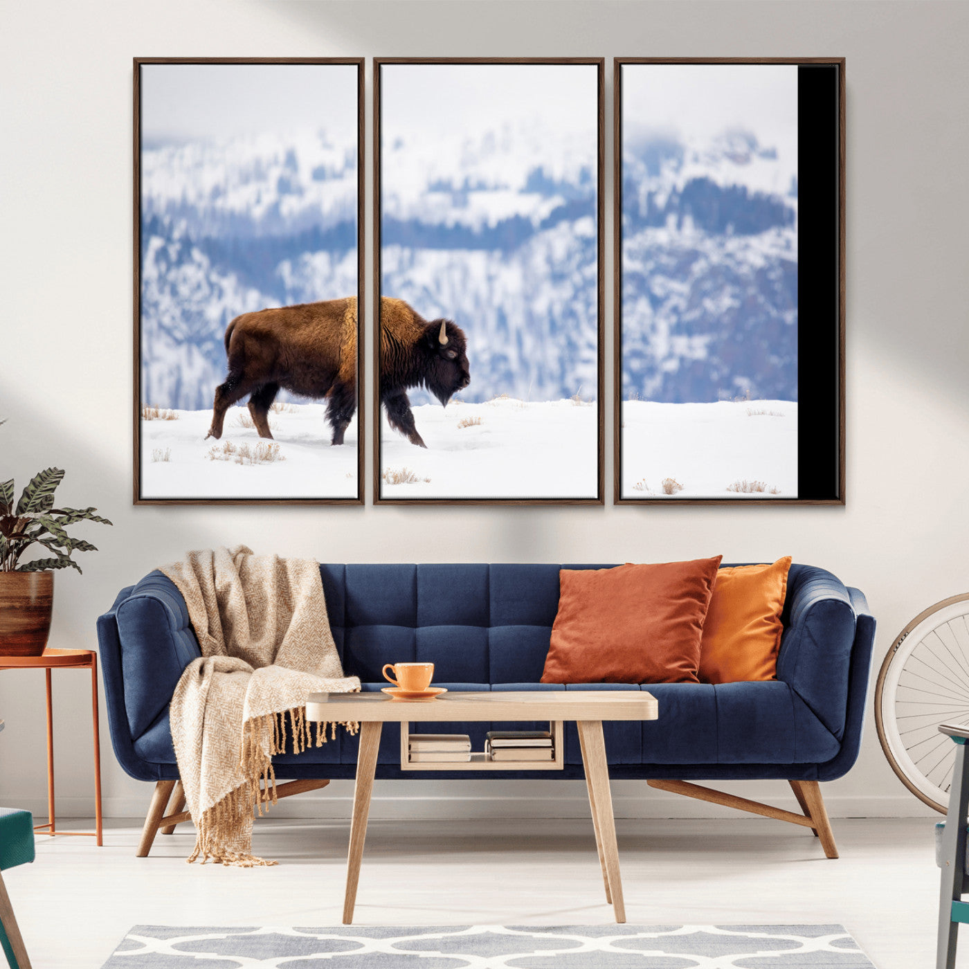 A lone bison walks across snowy ground with blue-toned mountain range behind, ideal for rustic or western farmhouse interiors.