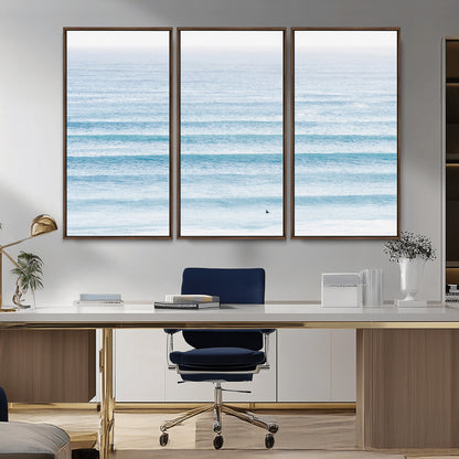 Minimalist ocean view with soft blue waves and a lone surfer, creating a serene and airy coastal aesthetic, perfect for tranquil home decor.