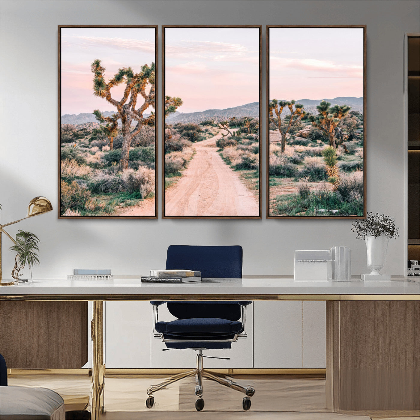 A dusty road winding through Joshua Tree National Park, framed by iconic twisted trees and warm desert tones under a soft pastel sky.
