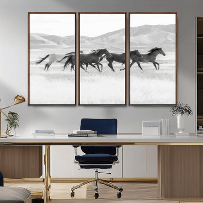 A black and white image of wild horses running freely across an open grassland, capturing the power and beauty of untamed nature in a rustic western setting.